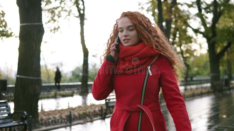 Młoda piękna kobieta opowiada na jej telefonie komórkowym na tle Z podnieceniem, szczęśliwy czerwony kędzierzawy z włosami dziewc