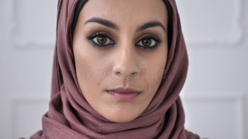 Młoda piękna poważna Indiańska dziewczyna patrzeje kamerę z przebijaniem w nosie w różowym hijab Portret, drzewo, biały