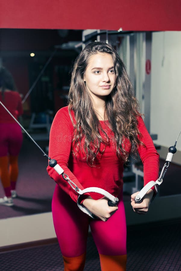 Młoda piękna sportowa dziewczyna trenuje na symulancie w gym sporty kobieta w czerwonych leggings robi ćwiczeniu zdjęcie stock Młoda piękna sportowa dziewczyna trenuje na symulancie w gym sporty kobieta w czerwonych leggings robi ćwiczeniu zdjęcie stock