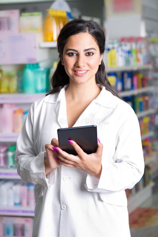 Młoda przystojna farmaceuta z pastylką w aptece obraz stock