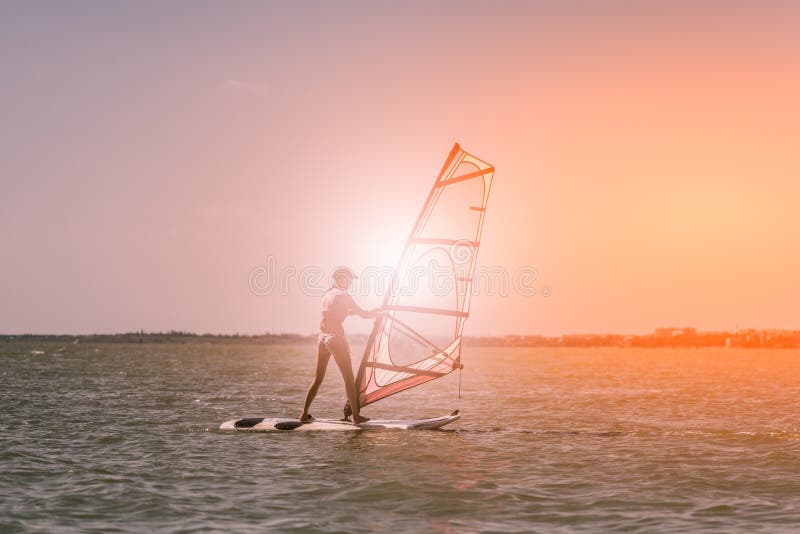 Młoda sportowa szczupła dziewczyna żegluje na windsurf desce w otwartym morzu na wakacje przy kurortem _ obraz stock Młoda sportowa szczupła dziewczyna żegluje na windsurf desce w otwartym morzu na wakacje przy kurortem _ obraz stock