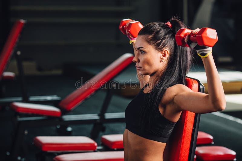 Młoda sporty kobieta robi ćwiczeniom z dumbbells w gym zdjęcia stock Młoda sporty kobieta robi ćwiczeniom z dumbbells w gym zdjęcia stock