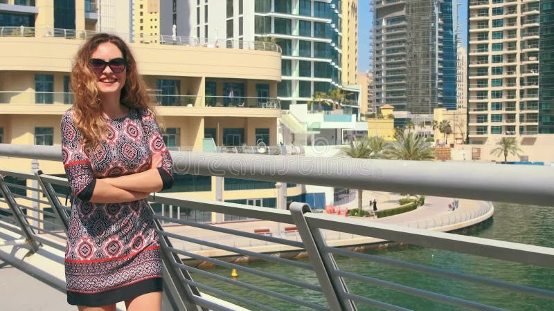 Młoda szczęśliwa kobieta spaceruje po moście Dubai Marina. Ciesz się miejską wodą rzeczną. Długie włosy blond zbiory
