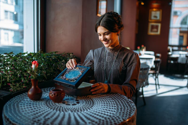 Młoda szczęśliwa kobieta w kawiarni z szkatułą i biżuterią zdjęcie stock Młoda szczęśliwa kobieta w kawiarni z szkatułą i biżuterią zdjęcie stock