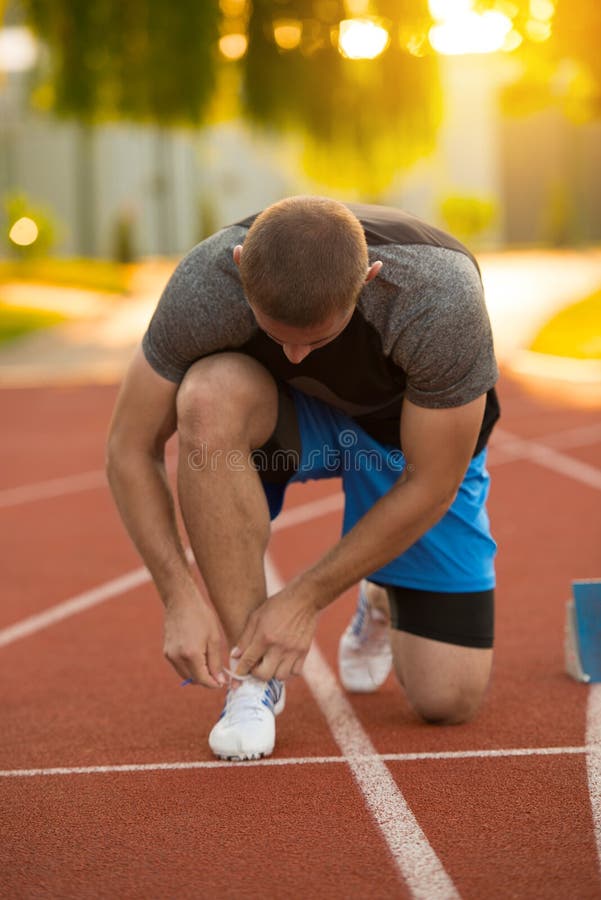 Młodego Człowieka biegacz wiąże jego buty na bieg śladzie Shoelaces, Miastowy jogger obrazy stock
