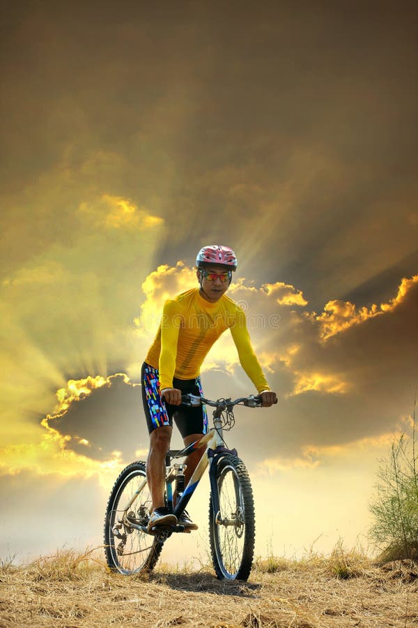 Młodego człowieka moutain roweru jeździecki mtb na gruntowej diunie przeciw ciemniusieńkiemu niebu w wieczór tła use dla sporta cz