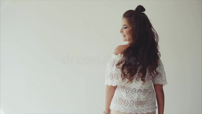 Młodej kobiety brunetka pozuje w studiu na białym tle i odprowadzeniu kamera