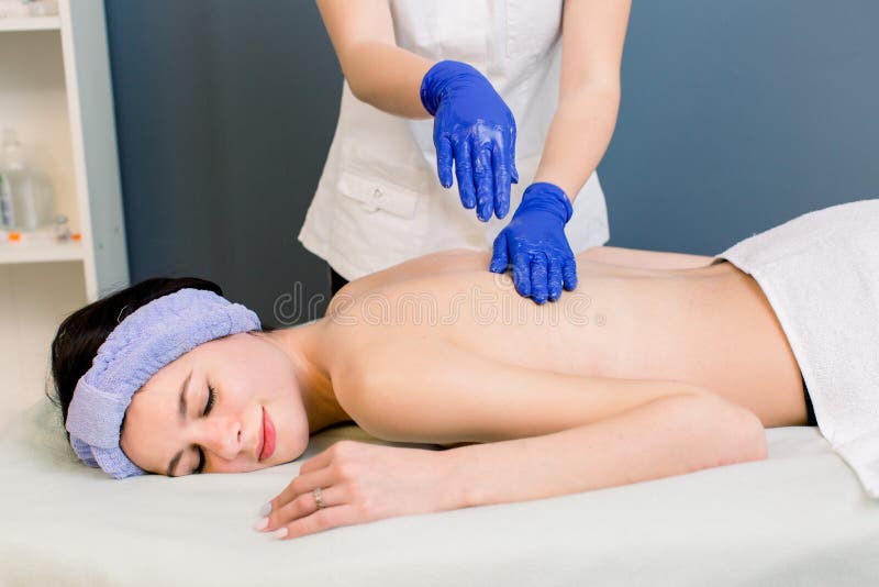 Młodej kobiety cosmetologist robi z powrotem masażowi przy zdroju salonem dla młodej ładnej dziewczyny fotografia stock Młodej kobiety cosmetologist robi z powrotem masażowi przy zdroju salonem dla młodej ładnej dziewczyny fotografia stock