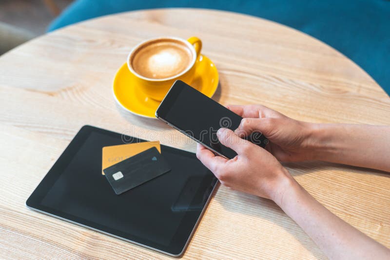 Młodej kobiety obsiadanie w kawiarni, smartphone, pastylce i karcie kredytowej używać, obraz royalty free Młodej kobiety obsiadanie w kawiarni, smartphone, pastylce i karcie kredytowej używać, obraz royalty free
