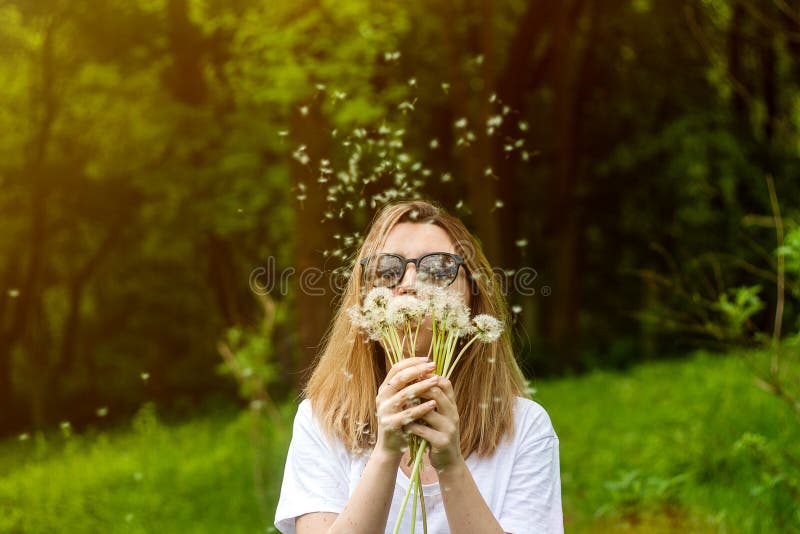 Młodej kobiety podmuchowy dandelion w lato parku Zielony lasowy piękny tło fotografia stock Młodej kobiety podmuchowy dandelion w lato parku Zielony lasowy piękny tło fotografia stock