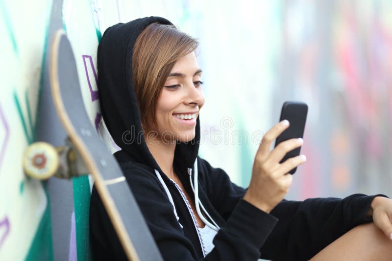 Młodej łyżwiarki szczęśliwa nastoletnia dziewczyna używa mądrze telefon fotografia royalty free