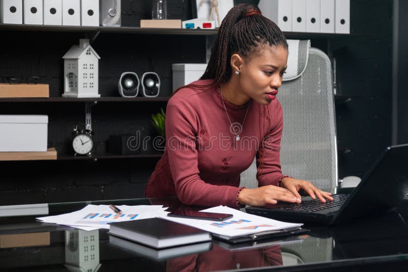 Młody afroamerykański bizneswoman pracuje na laptopie w biurze obrazy stock Młody afroamerykański bizneswoman pracuje na laptopie w biurze obrazy stock