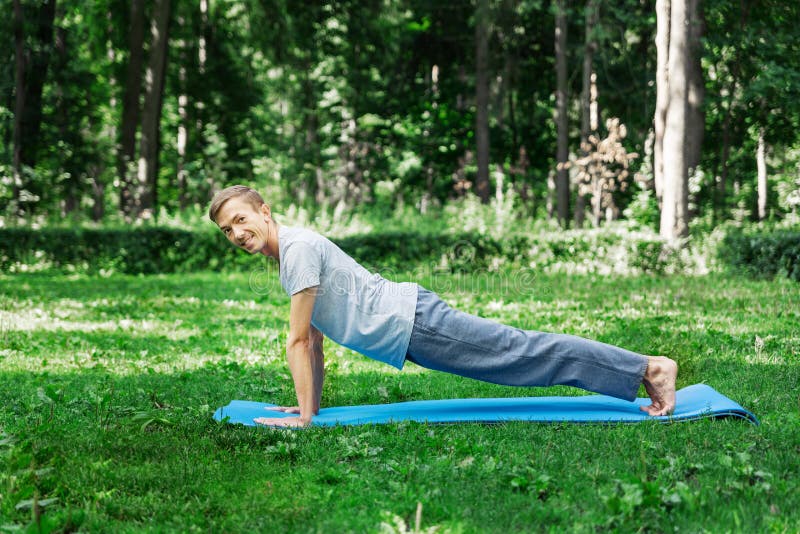 MÅ‚ody atrakcyjny mężczyzna wchodzi po sporty lub jogÄ™ na trawniku w parku zdjęcie royalty free MÅ‚ody atrakcyjny mężczyzna wchodzi po sporty lub jogÄ™ na trawniku w parku zdjęcie royalty free