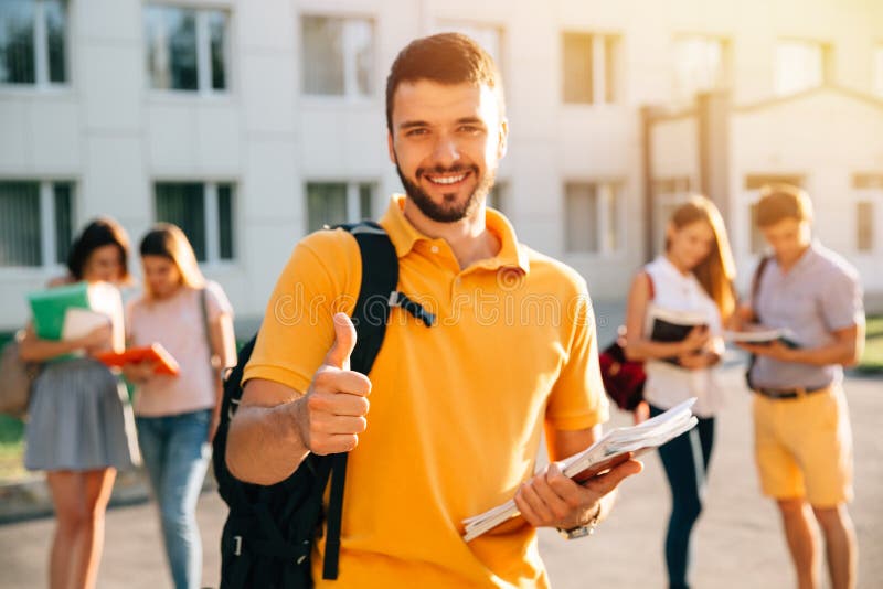 Młody atrakcyjny uśmiechnięty studencki pokazuje kciuk w górę outdoors na kampusie przy uniwersytetem zdjęcie royalty free Młody atrakcyjny uśmiechnięty studencki pokazuje kciuk w górę outdoors na kampusie przy uniwersytetem zdjęcie royalty free