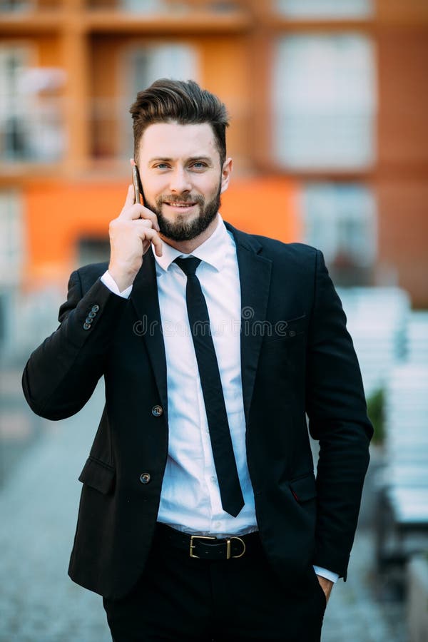 Młody brodaty przystojny biznesmen opowiada na jego telefonie komórkowym w miasto ulicie outdoors zdjęcia royalty free Młody brodaty przystojny biznesmen opowiada na jego telefonie komórkowym w miasto ulicie outdoors zdjęcia royalty free