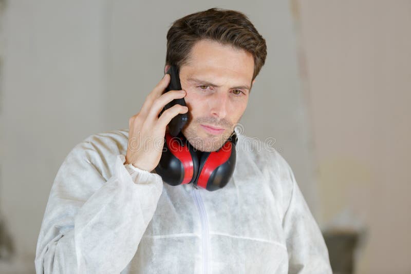 Młody budowniczy dogląda budowę używać telefon zdjęcia stock Młody budowniczy dogląda budowę używać telefon zdjęcia stock
