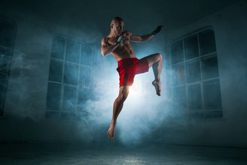 Młody człowiek kickboxing w błękita dymu obraz stock Młody człowiek kickboxing w błękita dymu obraz stock