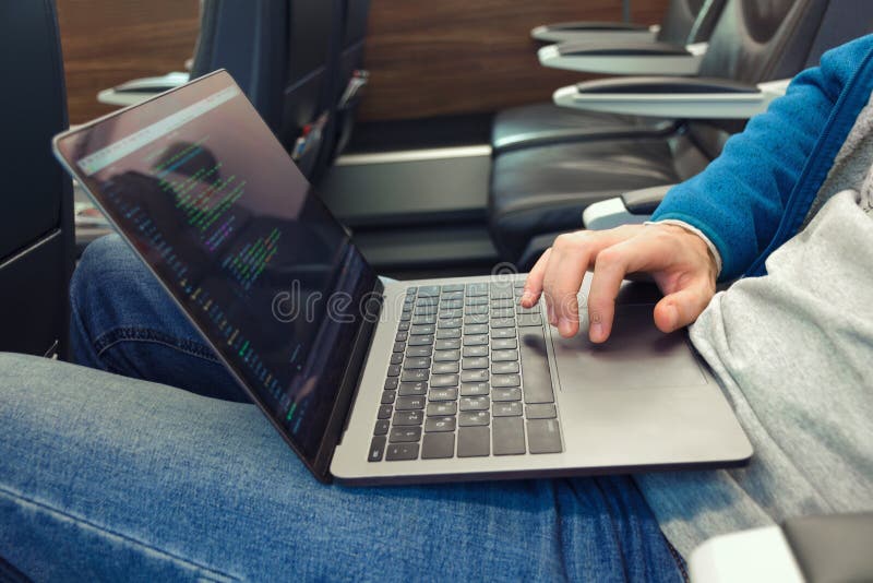 Młody człowiek pisze oprogramowanie kodzie na laptopie w transporcie w cajgach fotografia stock Młody człowiek pisze oprogramowanie kodzie na laptopie w transporcie w cajgach fotografia stock