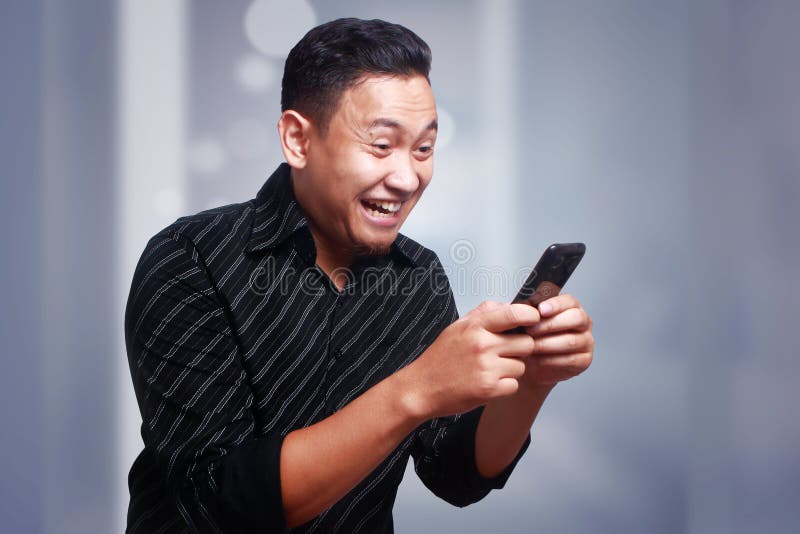 Młody Człowiek Texting Czytelniczego gawędzenie na Jego telefonie, ono Uśmiecha się Szczęśliwy fotografia stock Młody Człowiek Texting Czytelniczego gawędzenie na Jego telefonie, ono Uśmiecha się Szczęśliwy fotografia stock