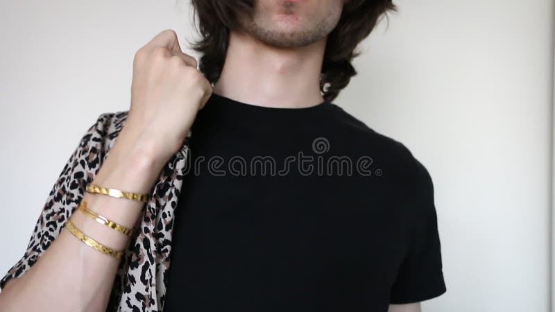 Młody kaukaski mężczyzna nakładający na lamparta koszulkę z nadrukiem w złotej bransoletce z czarną koszulką pod spodem