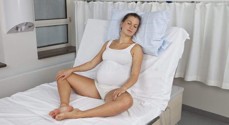 Młody kobieta w ciąży siedzieć pionowy na doręczeniowym łóżku