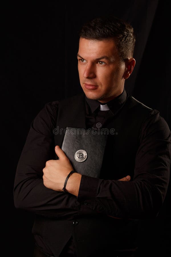 Młody księdza mienie i crypto biblia z bitcoin zdjęcia stock Młody księdza mienie i crypto biblia z bitcoin zdjęcia stock