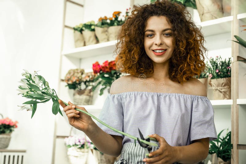 Młody kędzierzawy uczeń cieszy się jej na pół etatu pracę w flowershop zdjęcia royalty free Młody kędzierzawy uczeń cieszy się jej na pół etatu pracę w flowershop zdjęcia royalty free