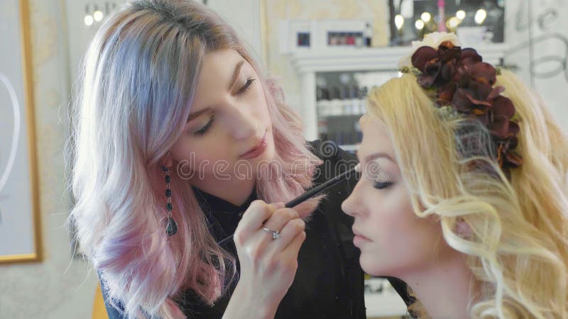 Młody makeup artysta stosuje kosmetyki na wzorcowym ` s ono przygląda się zdjęcia royalty free Młody makeup artysta stosuje kosmetyki na wzorcowym ` s ono przygląda się zdjęcia royalty free