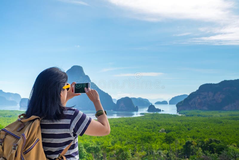 Młody podróżnik kobiety backpacker używa telefon komórkowego bierze fotografię piękny wschód słońca natura na szczyciefal tg0 0n zdjęcie royalty free Młody podróżnik kobiety backpacker używa telefon komórkowego bierze fotografię piękny wschód słońca natura na szczyciefal tg0 0n zdjęcie royalty free