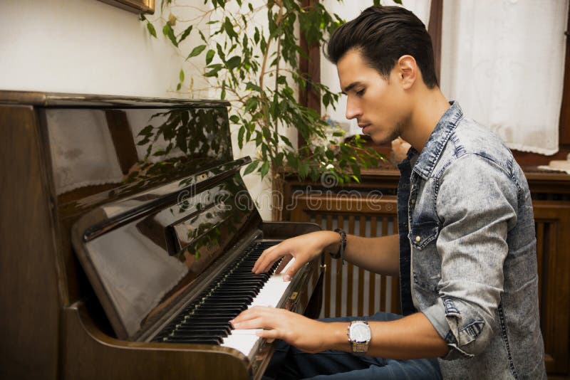 Młody przystojny męski artysta bawić się klasycznego pionowego pianino