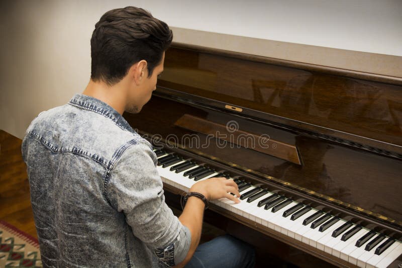 Młody przystojny męski artysta bawić się klasycznego pionowego pianino