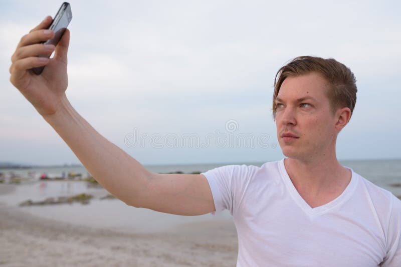 Młody przystojny mężczyzna bierze selfie obrazek z telefonem komórkowym przy th zdjęcia stock Młody przystojny mężczyzna bierze selfie obrazek z telefonem komórkowym przy th zdjęcia stock