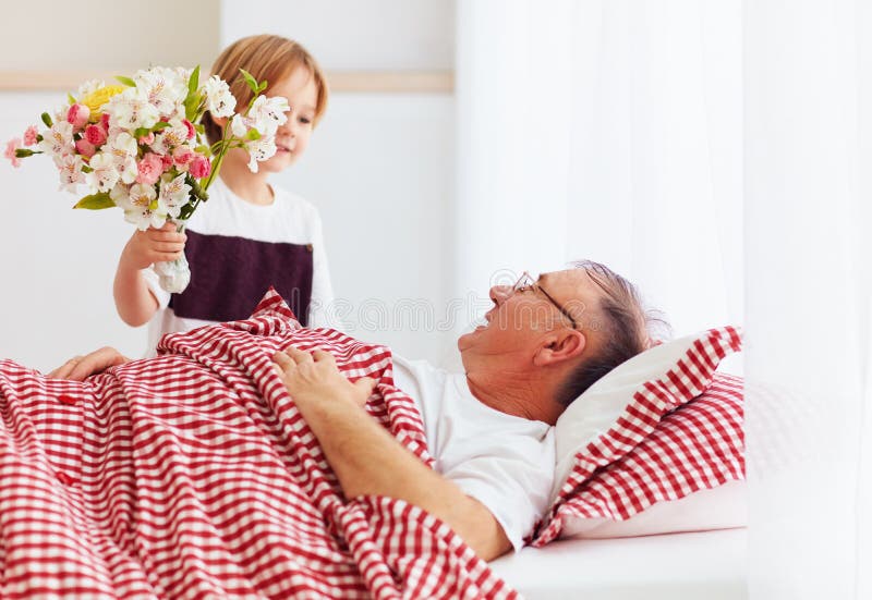 Młody wnuk z kwiatu bukietem przychodził odwiedzać jego chorego dziadunia w szpitalnym oddziale obrazy stock Młody wnuk z kwiatu bukietem przychodził odwiedzać jego chorego dziadunia w szpitalnym oddziale obrazy stock