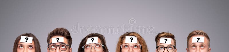 Group of puzzled young people with paper stickers with question mark on foreheads looking up while playing Who Am I game on gray background. Group of puzzled young people with paper stickers with question mark on foreheads looking up while playing Who Am I game on gray background