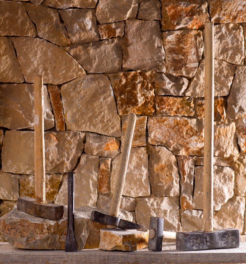 Hammer mason tools of stonecutter masonry work in a contruction stone wall. Hammer mason tools of stonecutter masonry work in a contruction stone wall