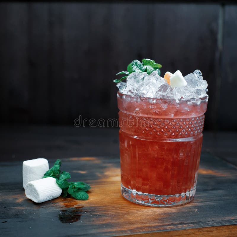 Na brązie drewniany stół w kawiarni jest słodkim czerwonym koktajlem z dodatkiem: martini, ajerówka, tonika, kostka lodu obrazy royalty free Na brązie drewniany stół w kawiarni jest słodkim czerwonym koktajlem z dodatkiem: martini, ajerówka, tonika, kostka lodu obrazy royalty free