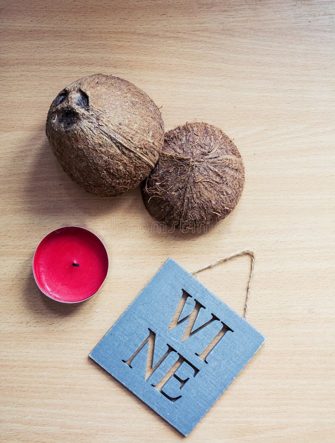 Na drewnianym stole oddzielnie warty czerwoną świeczkę ` wina ` pastylka z inskrypcją Kokosowa skorupa na beżowym drewnianym stol fotografia stock Na drewnianym stole oddzielnie warty czerwoną świeczkę ` wina ` pastylka z inskrypcją Kokosowa skorupa na beżowym drewnianym stol fotografia stock