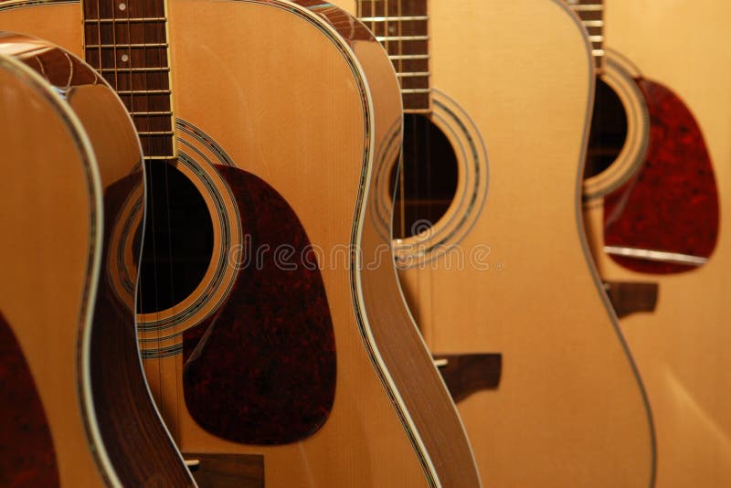 Four wood-colored guitars standing in a row. Focus on second guitar. Four wood-colored guitars standing in a row. Focus on second guitar.