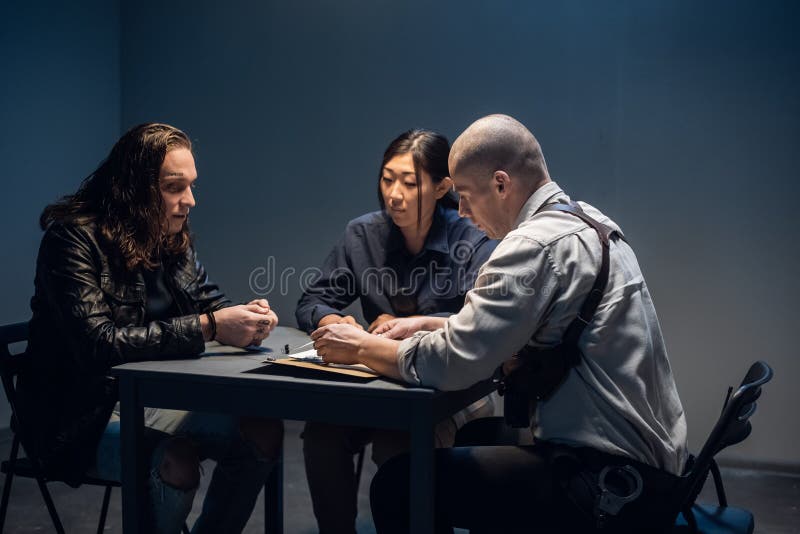 In the police station&#x27;s interrogation room, good and bad cops are questioning a theft suspect in a leather jacket. In the police station&#x27;s interrogation room, good and bad cops are questioning a theft suspect in a leather jacket