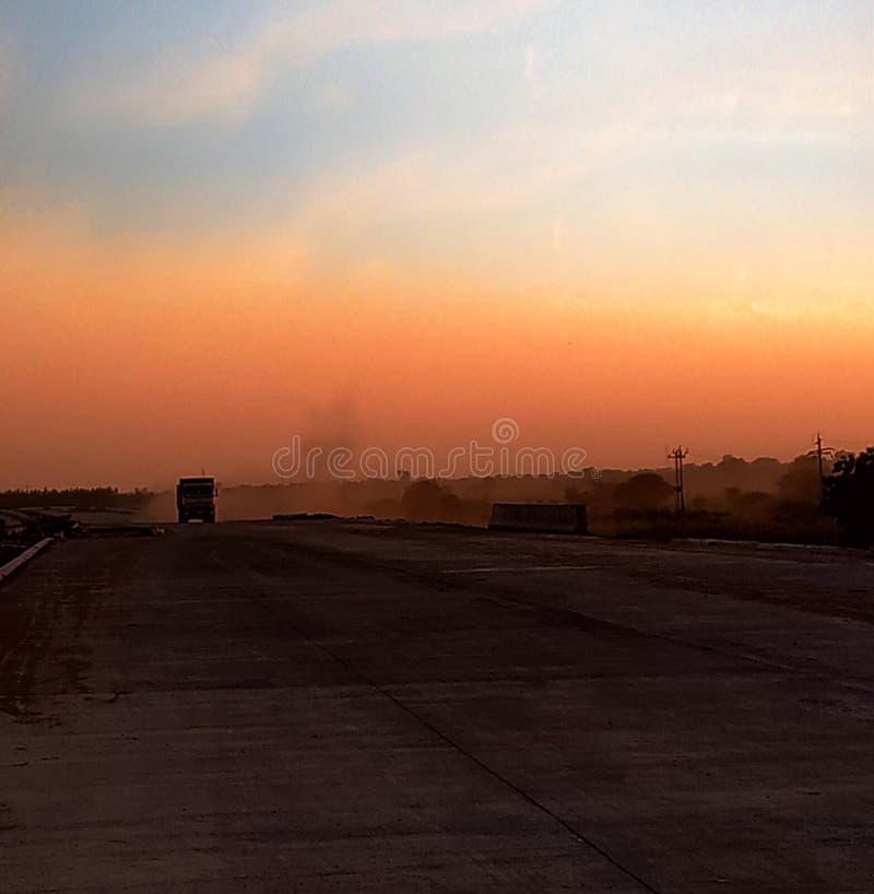 A dumper truck in the picture. Red orange color sky in early morning view. A dumper truck in the picture. Red orange color sky in early morning view