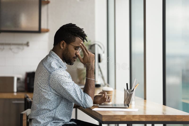 Nachdenklicher Afroamerikanergeschäftsmann der Datenzugriffsseiten-Ansicht, der an Forschungsprojekt funktioniert stockfoto