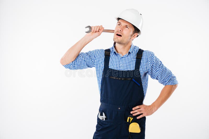 Nachdenklicher hübscher junger Erbauer, der denkt und schaut, hochhalten Schlüssel stockbild Nachdenklicher hübscher junger Erbauer, der denkt und schaut, hochhalten Schlüssel stockbild