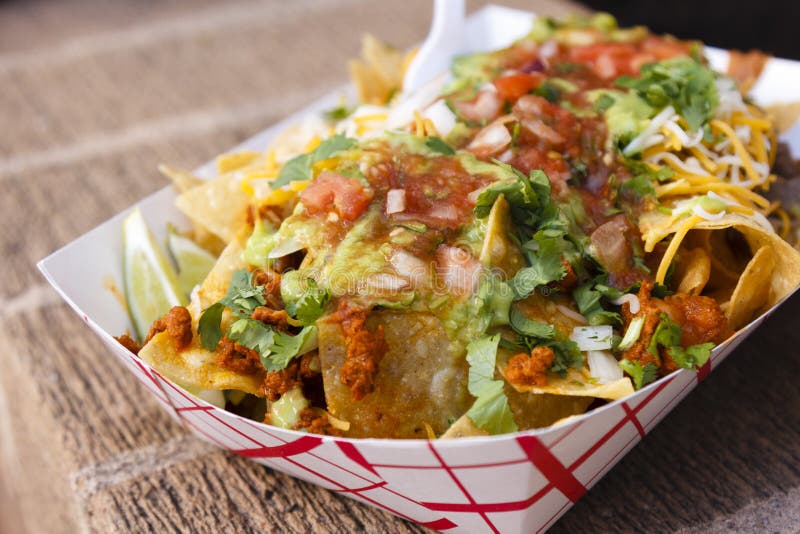 A plate of nachos with ground meat and salsa topped with cheese. A plate of nachos with ground meat and salsa topped with cheese