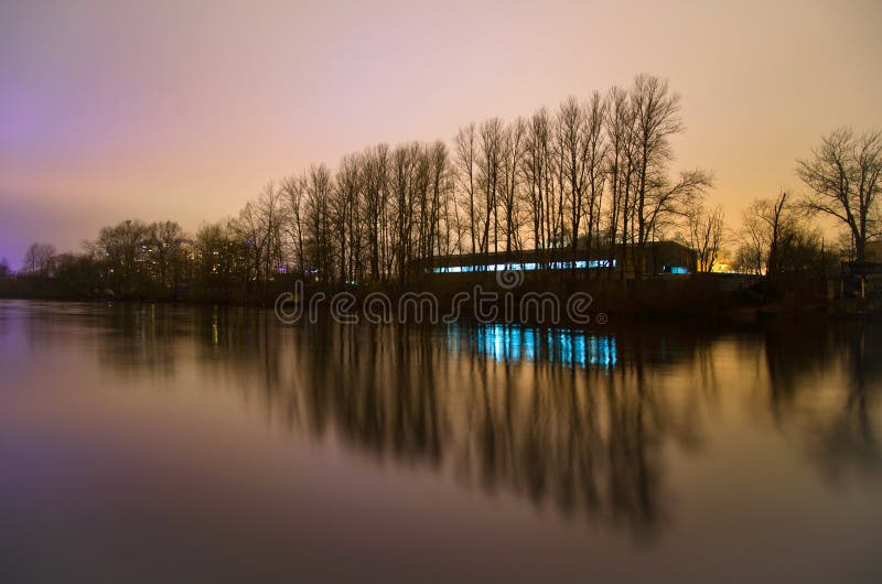 Nacht leidt de rand van de stad, de bezinning van de bomen in de rivier tot de vorm van een Kerstboom royalty-vrije stock afbeelding Nacht leidt de rand van de stad, de bezinning van de bomen in de rivier tot de vorm van een Kerstboom royalty-vrije stock afbeelding