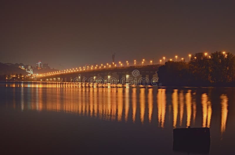Nachtcityscape met Paton-brug over Dnieper-rivier Het monument van het vaderland bij de achtergrond Stadslichten in het water wor royalty-vrije stock afbeeldingen Nachtcityscape met Paton-brug over Dnieper-rivier Het monument van het vaderland bij de achtergrond Stadslichten in het water wor royalty-vrije stock afbeeldingen