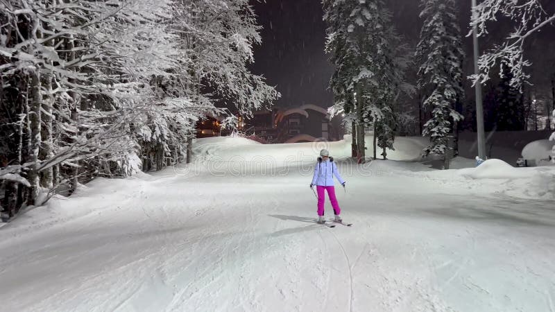 Nachtskiën op de helling van de verlichting met sneeuwbedekte bomen met vorst