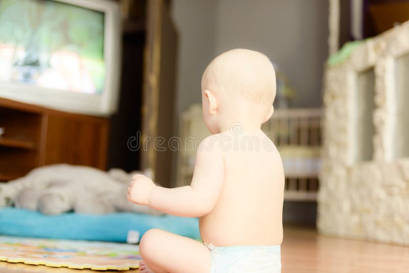 Nacktes Baby, das fernsieht, auf dem Boden zu sitzen lizenzfreies stockbild Nacktes Baby, das fernsieht, auf dem Boden zu sitzen lizenzfreies stockbild