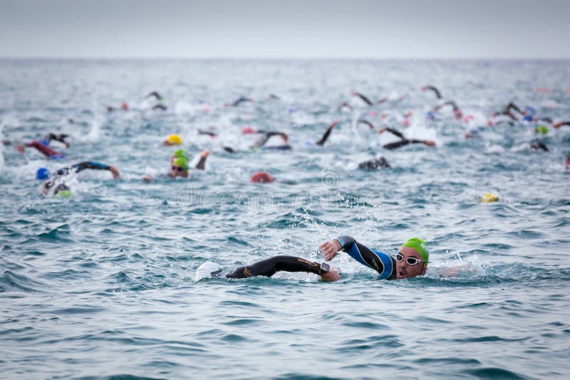 Nadada de Triathletes en el comienzo de la competencia del triathlon de Ironman fotografía de archivo libre de regalías Nadada de Triathletes en el comienzo de la competencia del triathlon de Ironman fotografía de archivo libre de regalías
