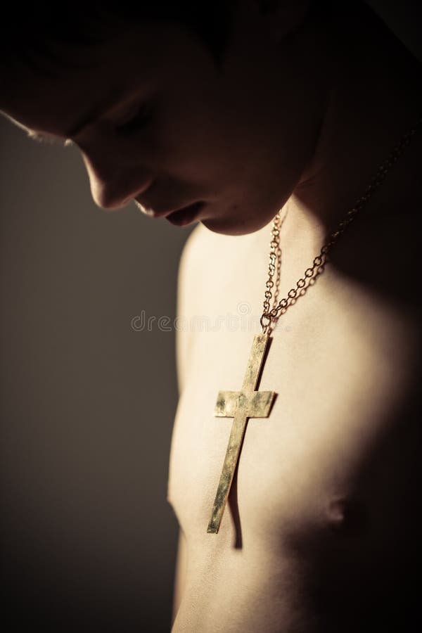Nadenkende Jongen die Kruis op Ketting dragen rond Hals stock foto Nadenkende Jongen die Kruis op Ketting dragen rond Hals stock foto