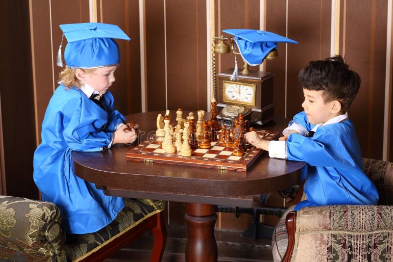 Two thoughtful boys in blue suits play chess. Two thoughtful boys in blue suits play chess